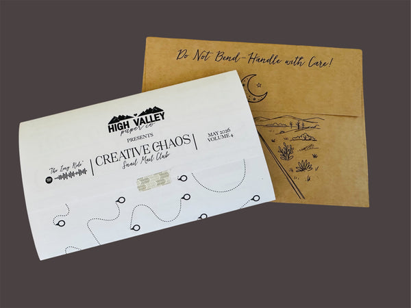 White envelope with black text and brown envelope with black text on a dark gray background